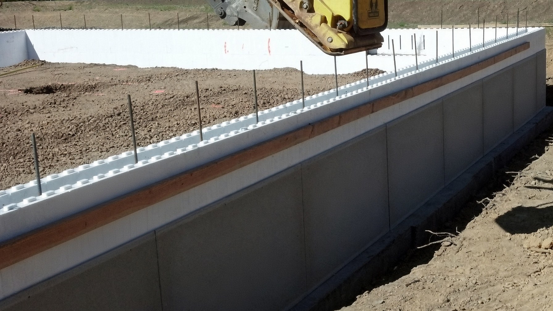 Stacked ICF wall on a jobsite — interlocking foam, rebar in the cells